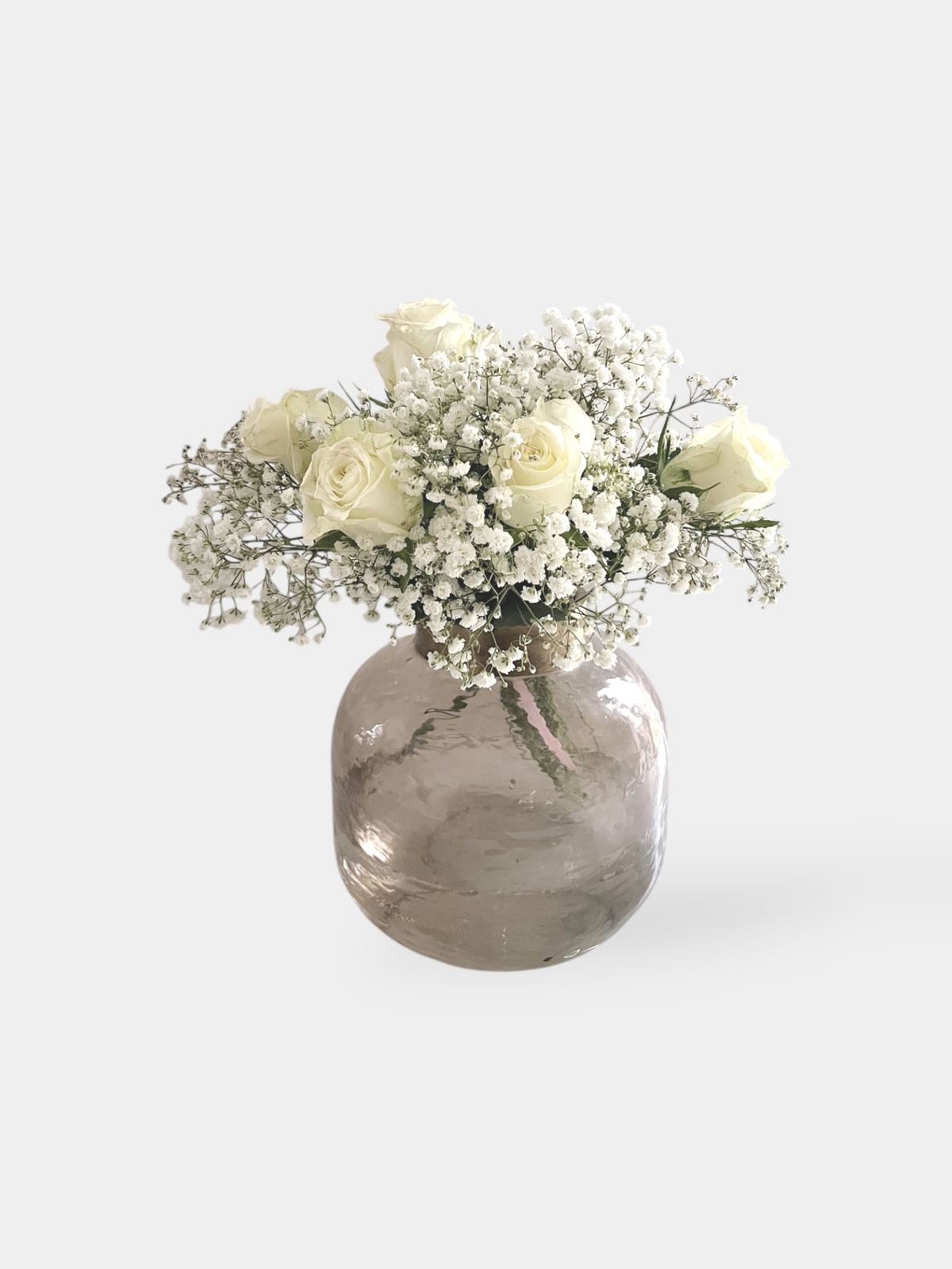 A bunch of white roses and dried baby's breath arranged in a clear glass vase with a marble-like finish. Snow Fairy Bunch | FLOWERFIX