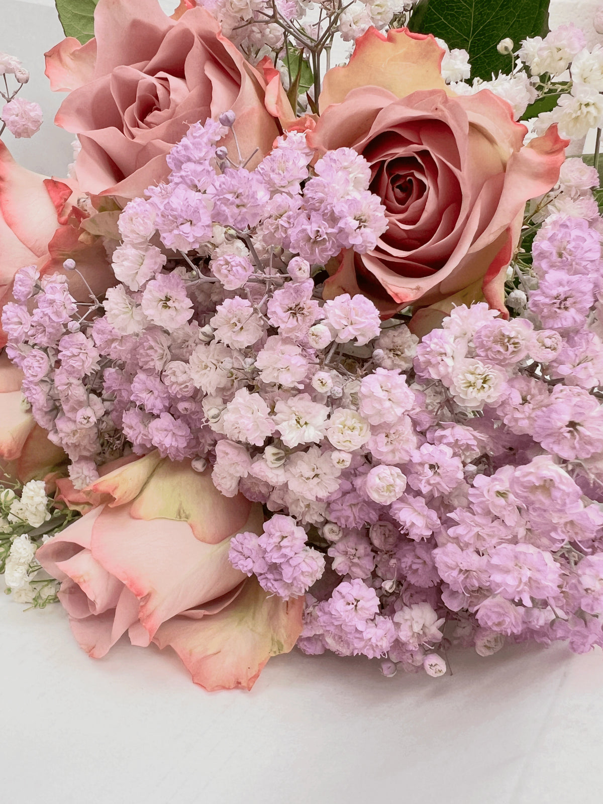 Bouquet of lilac and white roses with baby's breath on a light background. Fairy Bunch | FLOWERFIX