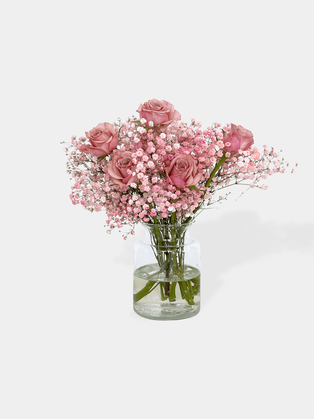 Bouquet of pink roses and baby's breath in a clear vase on a white background. The Princess Bunch | FLOWERFIX